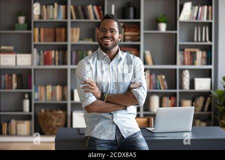 Ritratto sorridente uomo d'affari afro-americano in piedi vicino alla scrivania Foto Stock