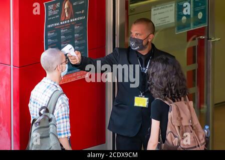 Misurazione della temperatura corporea all'ingresso di un cinema O teatro per prevenire pandemie COVID-19 o Coronavirus con infrarossi rilevatore di febbre remoto Foto Stock