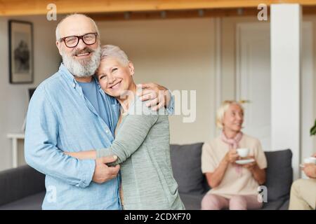 Ritratto di felice coppia anziana che si abbracciano e sorridendo a casa con la fotocamera Foto Stock