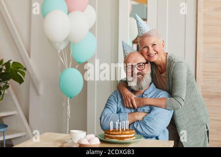 Ritratto di felice coppia senior abbracciando e sorridendo alla macchina fotografica mentre festeggiamo il compleanno Foto Stock