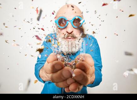 Ritratto dell'uomo anziano in occhiali da sole sotto i confetti al partito isolato su sfondo bianco Foto Stock