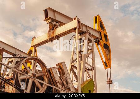 Attrezzatura per pompa dell'olio. Produzione di petrolio e gas. Sito di giacimento petrolifero. Il martinetto della pompa è in funzione. Trivellazione per produzione di combustibili fossili e greggio Foto Stock