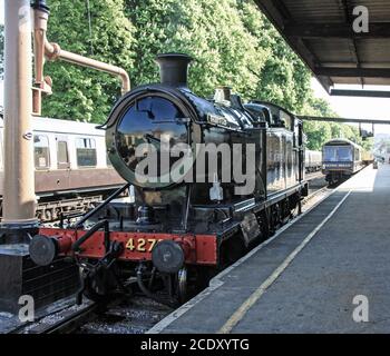 Il motore ferroviario Hercules sulla piattaforma della stazione di Paignton. La locomotiva a vapore corre lungo la linea storica della Dartmouth Railway. Nella distanza di Foto Stock