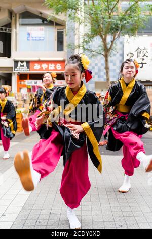 Primo piano della squadra giapponese di ballerini yosakoi che ballano con una giovane ballerina di fronte alla spettatrice, al festival Kyusyu Gassai, Kumamoto. Foto Stock