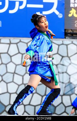 Giovane ballerina yosakoi in tunica blu yukata che tiene naruko, clapper in legno, mentre balla sul palco al festival di danza Kyusyu Gassai in Giappone. Foto Stock