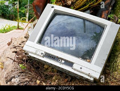 Un vecchio televisore analogico rotto è stato scaricato lungo la strada da un consumatore irresponsabile in Asia Foto Stock