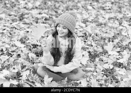 Allegro. Caldo accessorio di lana. Ragazza capelli lunghi faccia felice rientrano la natura dello sfondo. Tenervi caldi questo autunno. Il bambino nel cappello giallo all'esterno. Hat tenere in caldo. Usura del capretto morbido Caldo berretto lavorato a maglia. Foto Stock