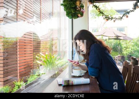 Belle donne asiatiche che bevono caffè caldo seduto sul divano vintage in caffetteria Foto Stock