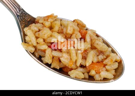 Nel vecchio cucchiaio d'oro c'è una piccola pila di cibo - grasso asiatico pilaf macro isolato Foto Stock