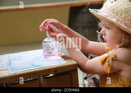 Bambina che usa l'igienizzatore per le mani durante la pandemia di Covid 19, 2020 Foto Stock