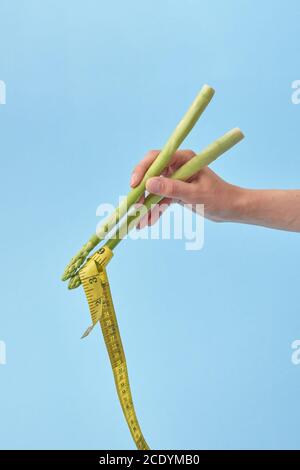 La mano femminile con bastoncini di asparagi sta prendendo nastro di misura. Foto Stock
