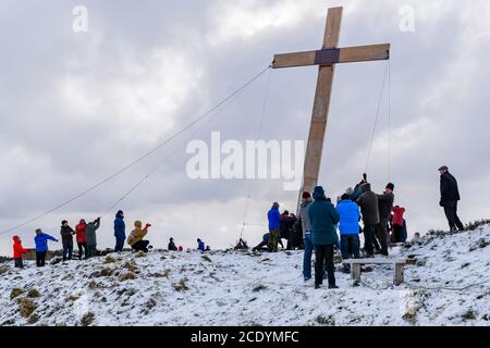 La gente (cristiani) usa le corde per sollevare e sollevare la Croce di Pasqua pesante enorme di legno (simbolo di fede) sulla cima della collina nevosa - la Chevin, Otley, Yorkshire, Regno Unito. Foto Stock