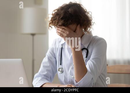 Primo piano infelice donna stressata medico coprendo il viso con la mano Foto Stock