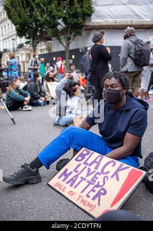 Londra, Regno Unito. 30 agosto 2020. Giovane protetore maschile, siede in strada con un banner che recita 'BLACK LIVES MATTER' durante la 'Million People March' da Notting Hill ad Hyde Park. Continuano le proteste contro la brutalità della polizia negli Stati Uniti e nel Regno Unito. Credit: Neil Atkinson/Alamy Live News. Foto Stock