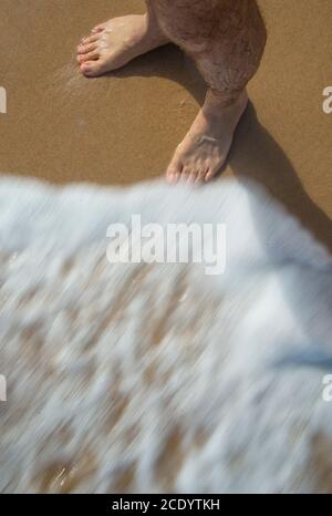 I piedi dell’uomo in riva al mare. Foto Stock