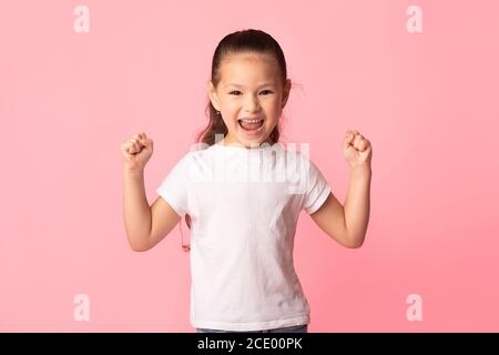 Bambina asiatica scuotendo pugni, facendo gesto vincitore Foto Stock