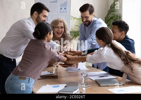Una leader femminile di mezza età che si unisce alle mani dei giovani colleghi. Foto Stock