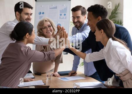 Felice gruppo internazionale che si unisce alle mani in cinque gesti. Foto Stock