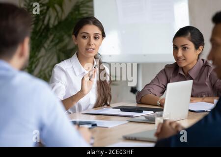 Giovane donna di etnia araba fiduciosa che discute le idee di progetto con i colleghi. Foto Stock