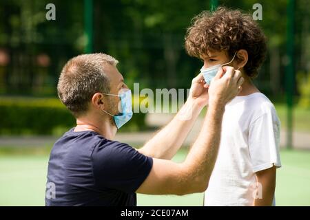 Papà mette una maschera protettiva sul suo bambino Foto Stock