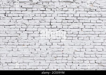 parete di mattone bianca ruvida con fondo di gesso che perde Foto Stock