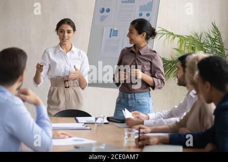 Colleghi di gara misti felici che presentano la strategia di marketing in ufficio. Foto Stock