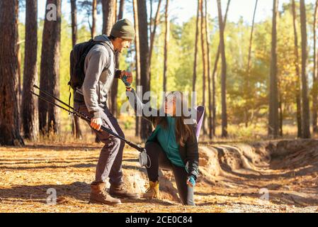 Bell'escursionista che aiuta la sua ragazza in salita nella foresta Foto Stock