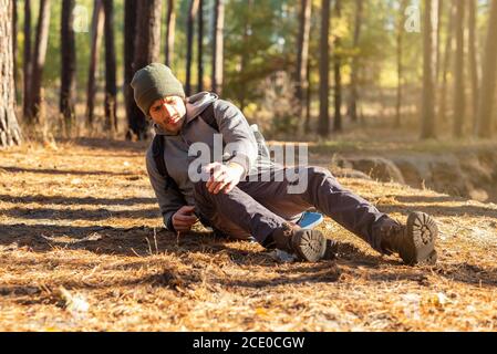 Uomo che ha dolore al ginocchio durante il viaggio in foresta Foto Stock