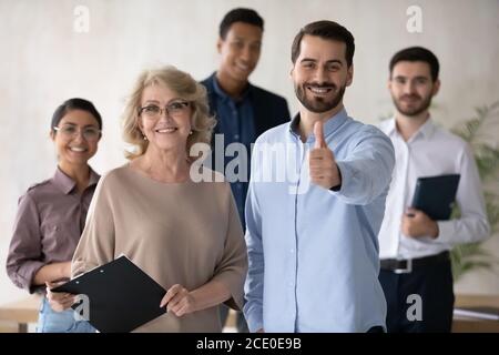 Ritratto di gruppo di sorridenti dipendenti multirazziali con leader senior più anziano. Foto Stock