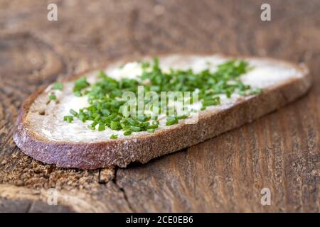 Pane con burro e erba cipollina su legno Foto Stock