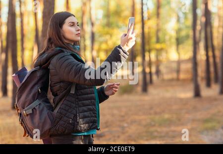 Ragazza concentrata in piedi in legno con smartphone Foto Stock