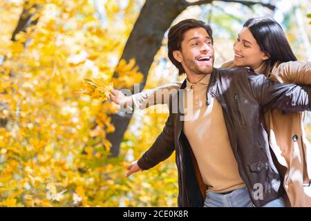 Uomo e donna in amore imitando aereo in parco d'oro Foto Stock