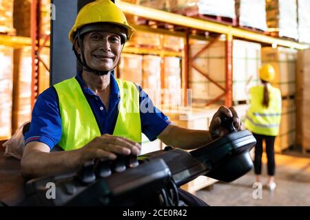 Lavoratore magazzino asiatico con carrello elevatore in magazzino Foto Stock
