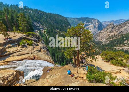 Yosemite, California, Stati Uniti - 24 luglio 2019: Persone che riposano sulla cima della cascata Nevada Fall sul fiume Merced dal Mist Trail a Yosemite Foto Stock