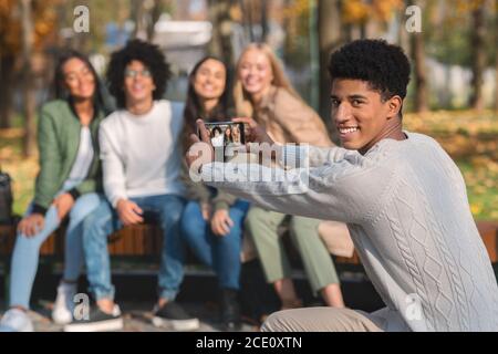 Sorridente ragazzo africano scattando foto dei suoi teen amici Foto Stock