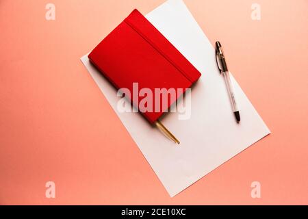 Notebook rosso copertina bianco foglio su sfondo rosa pastello stile con copyspace flatlay Foto Stock