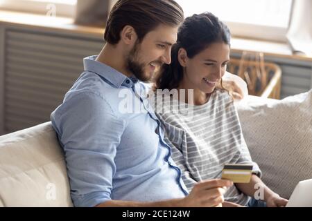 Felice giovane coppia di famiglia coinvolto nello shopping del Internet a casa. Foto Stock