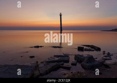 Faro di Kiipsaare a Saaremaa, Estonia. Iconico punto di riferimento locale - spiedire il faro abbandonato. Tramonto con un cielo di colore rosso. Foto Stock