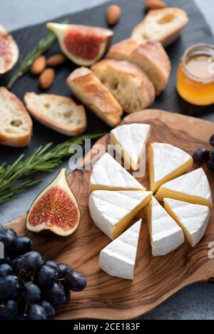 Piatto di formaggio Camembert con uva, fichi, miele e baguette. Piatto di formaggi Foto Stock
