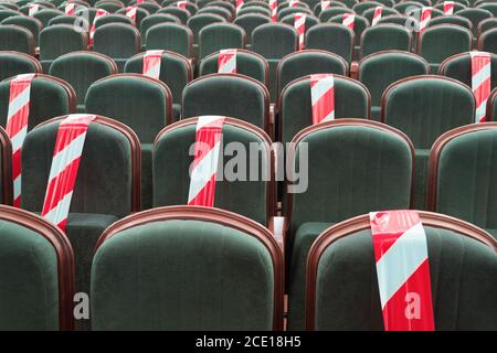 Necessità di sedersi su una sedia separata da un nastro nel cinema, teatro, auditorium. Mantenere una distanza sociale sicura in luoghi pubblici, incontri di Foto Stock