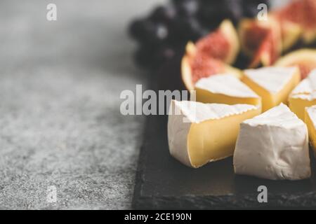 formaggio brie o camembert affettato con fichi e uva su tavola nera. Piastra di formaggio, spazio per la copia Foto Stock