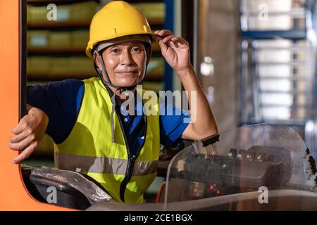 Lavoratore magazzino asiatico con carrello elevatore in magazzino Foto Stock