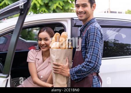 Donna asiatica prendere la borsa della spesa di consegna dal supermercato Drive Thru Foto Stock