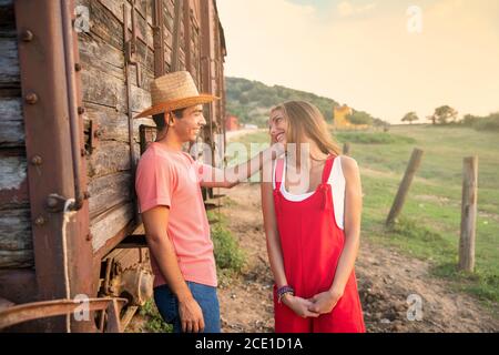 Giovani amici Flirtare e sorridere di fronte a un vagone di treno nel Ranch. Ranch Concept Photography Foto Stock