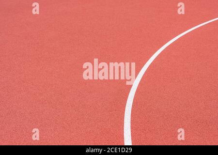 Primo piano su una linea bianca in erba rossa artificiale, su una strada di pallacanestro, pallamano, pallavolo, futsal, rugby, hockey e campo di calcio, in uno sport b Foto Stock