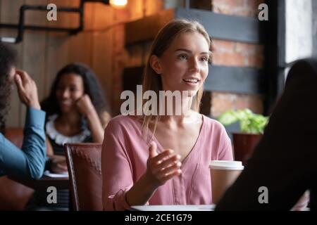 Sorridente bella giovane donna che parla al meeting in caffetteria Foto Stock