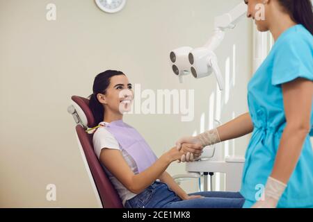 Donna sorridente paziente scuotendo la mano al dentista dopo il dente riuscito esame in clinica odontoiatrica Foto Stock