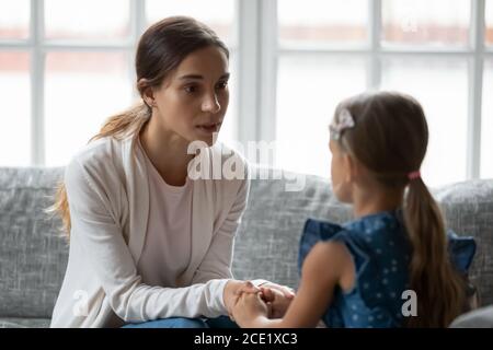 Preoccupata giovane mamma che sostiene, dando consigli alla piccola figlia. Foto Stock