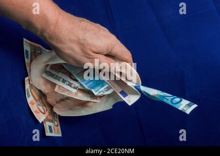 La mano prende una conchiglia in cui sono banconote in euro di tagli diversi Foto Stock