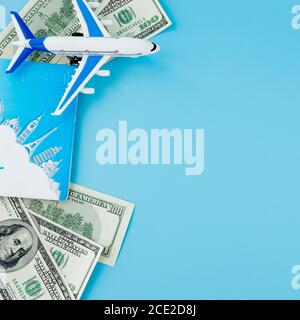 Passaporto con modello di aereo passeggeri e dollari su sfondo blu. Concetto di viaggio, spazio di copia. Foto Stock